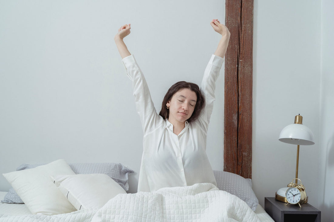 Femme fatiguée au réveil, assise sur son lit le matin