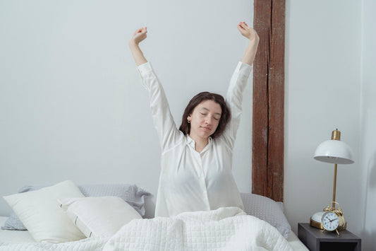 Femme fatiguée au réveil, assise sur son lit le matin
