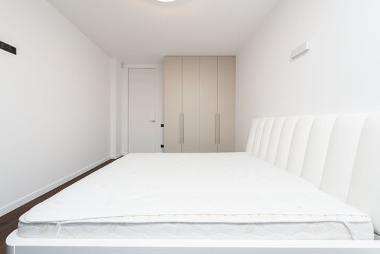 Matelas blanc posé sur un sommier dans une chambre minimaliste contemporaine