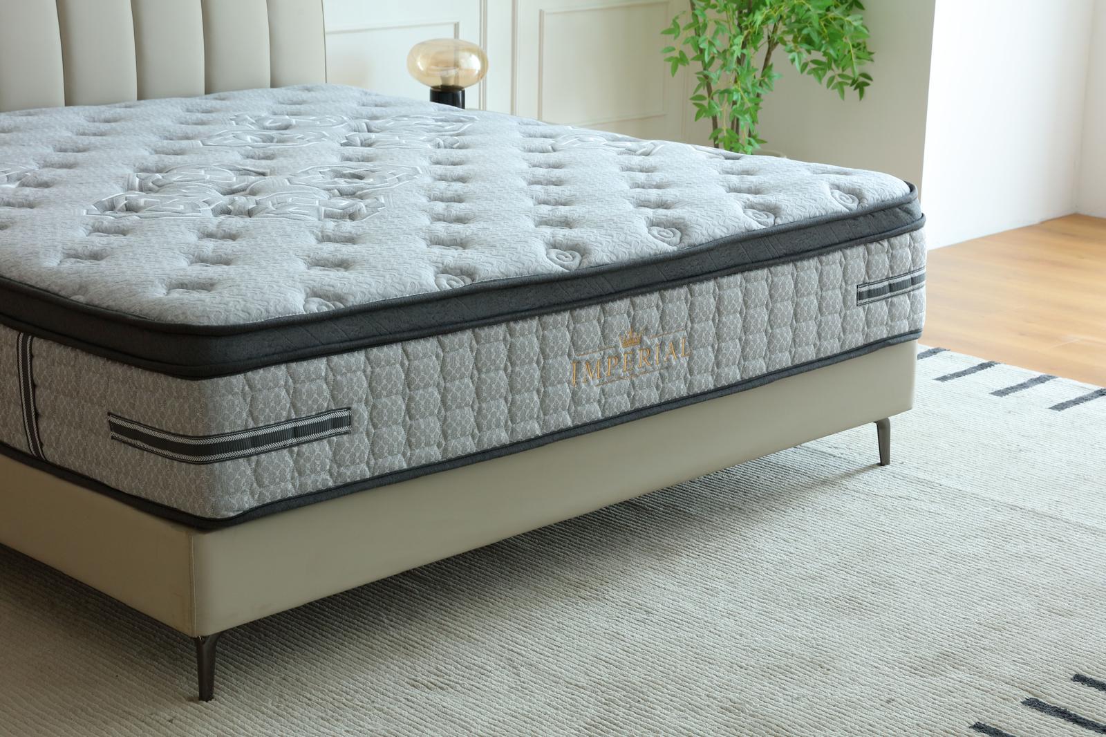 Matelas Imperial vu de trois quarts sur son lit, dans une chambre claire au tapis rayé
