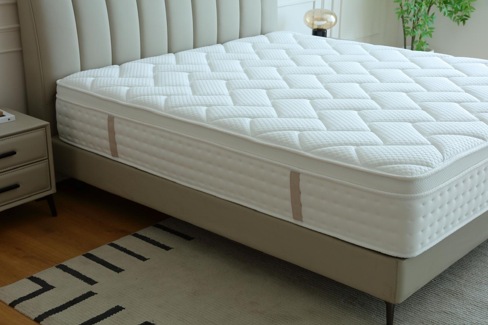 Matelas Palace vu de trois quarts sur son sommier, près d'une table de chevet