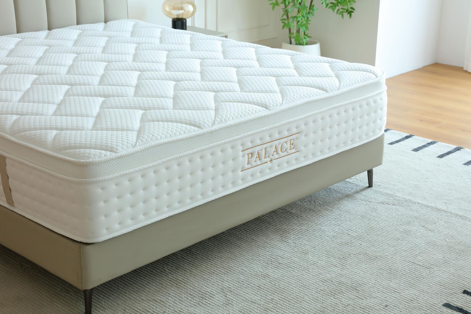 Matelas Palace posé sur son sommier beige, logo doré visible sur le bandeau latéral