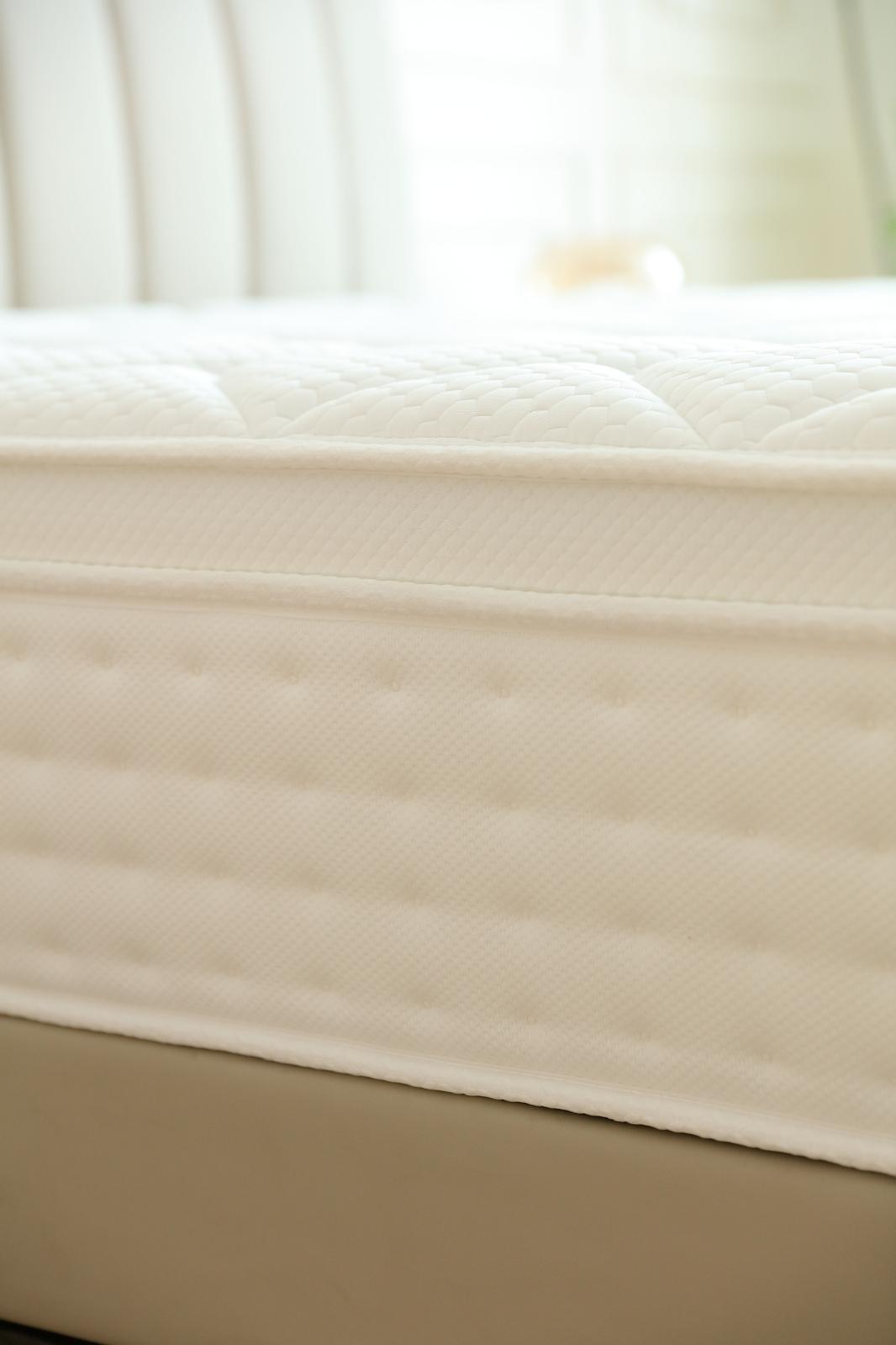 Gros plan sur le coin du matelas Palace devant une tête de lit capitonnée