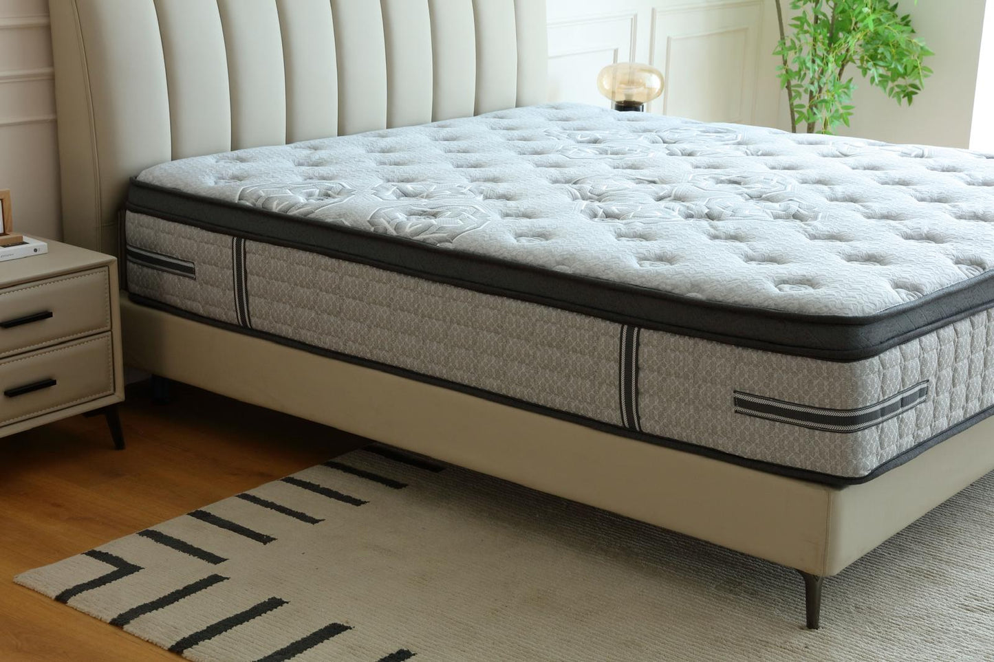 Matelas Imperial vu de côté sur son lit, près d'une table de chevet et d'une lampe